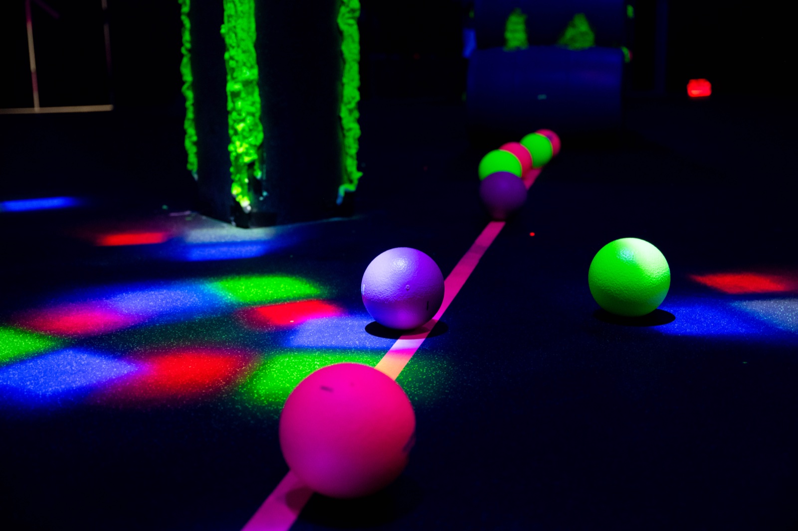 A row of glowing pink, purple and green balls along the center line of the dark arena